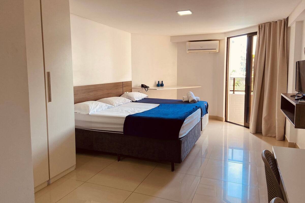 A hotel room with a bed, a desk, a chair, a TV, and a bathroom.