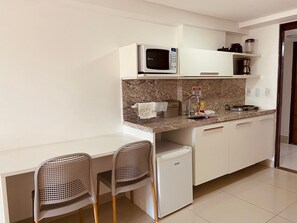 A compact kitchenette with a microwave, a coffee maker, and a small refrigerator. There are two chairs and a sink with a faucet. - Gold Flat by Apartamentos Jampa (João Pessoa)