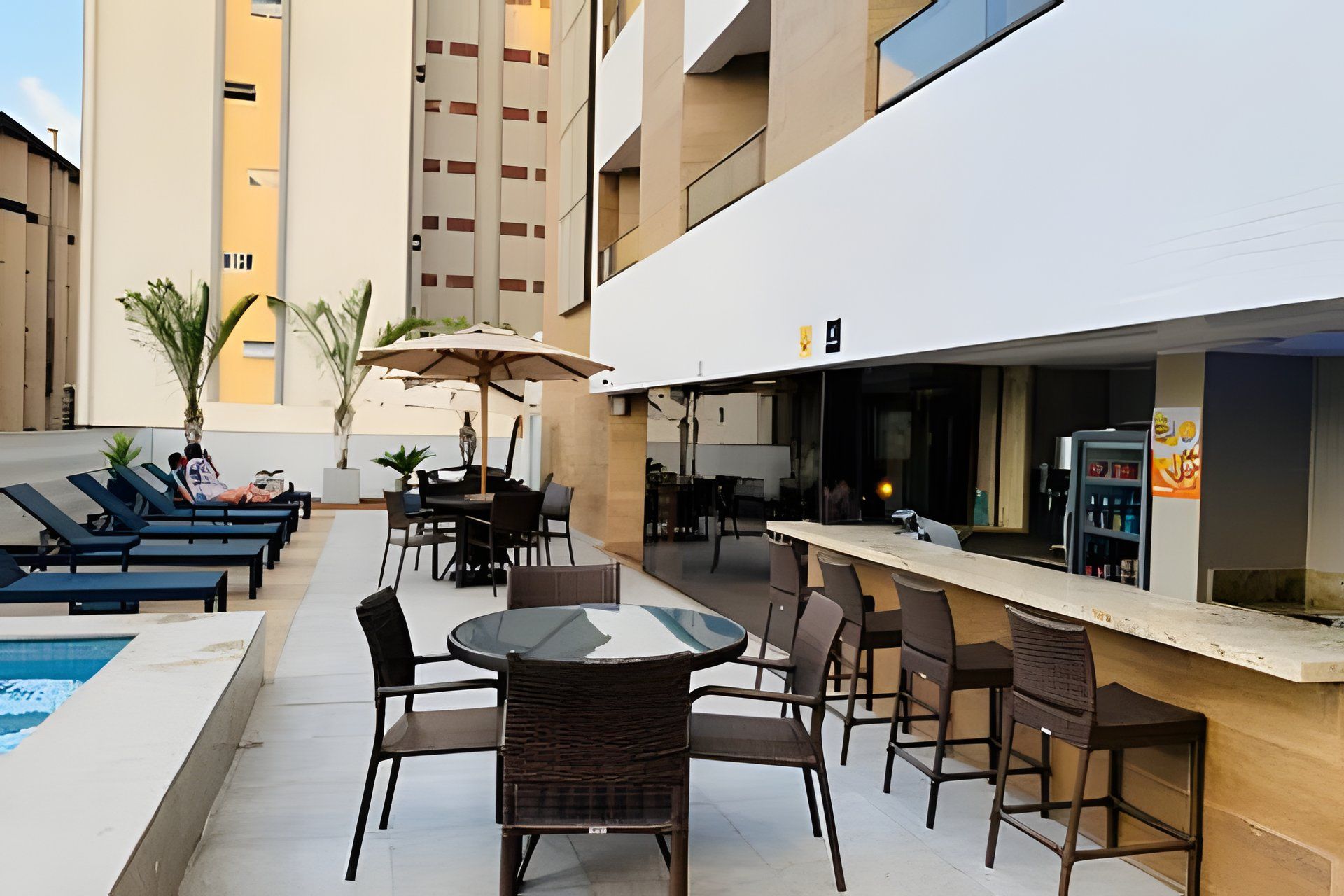 A rooftop bar with outdoor seating, a pool, and a bar counter.