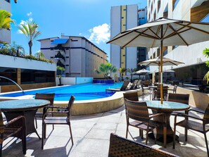 A rooftop pool area with lounge chairs and umbrellas, surrounded by modern buildings. - Gold Flat by Apartamentos Jampa (João Pessoa)