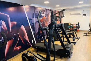 Un gimnasio con equipo de ejercicio, una cinta de correr y una pared con un cartel.