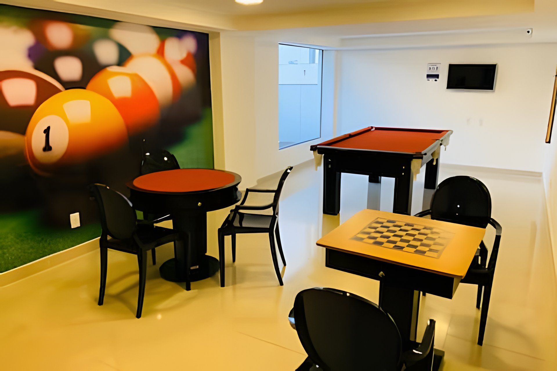 A billiards room with a pool table, a table with a chessboard, and a billiard cue rack.