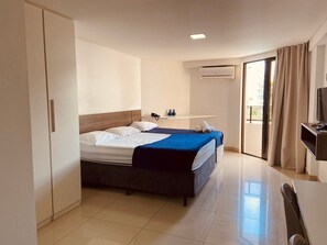 Una habitación de hotel con cama, escritorio, silla, televisor y baño.