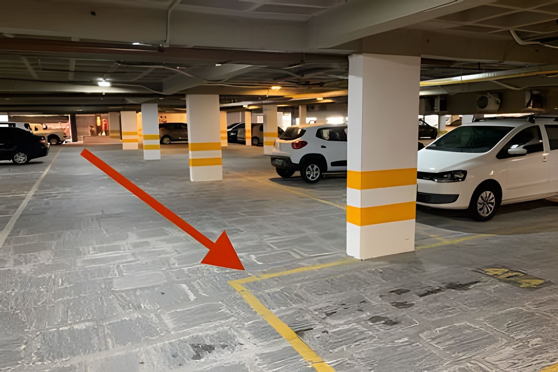 A multi-level parking garage with white pillars and yellow stripes, featuring several parked cars.