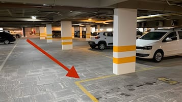 A multi-level parking garage with white pillars and yellow stripes, featuring several parked cars.