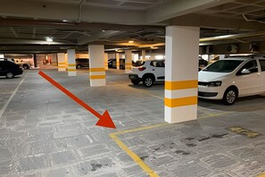 A multi-level parking garage with white pillars and yellow stripes, featuring several parked cars. - Gold Flat by Apartamentos Jampa (João Pessoa)