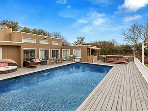 A modern house with a swimming pool, outdoor seating, and a deck.