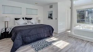 A modern bedroom with a large bed, a skylight, and a view of the outdoors. - Hamptons getaway (East Quogue)
