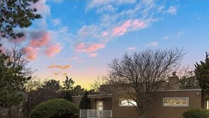 A residential house with a front yard, a driveway, and a well-maintained lawn. - Hamptons getaway (East Quogue)