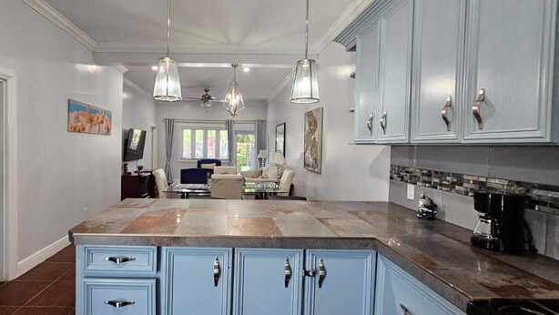 Een moderne keuken met blauwe kastjes, een groot eiland en hanglampen.