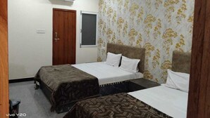 A room with two beds, a wooden door, an air conditioning unit, and a patterned wallpaper. - Hotel Somnath Inn (Ujjain)