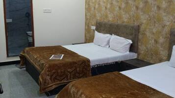 A hotel room with two single beds, a bathroom with a shower, and a patterned wall.