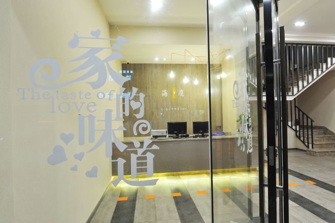 A reception area with a modern design, featuring a reception desk, computer monitors, and a staircase leading to an upper floor.