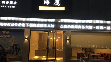 A hotel entrance with illuminated signage and a glass door.