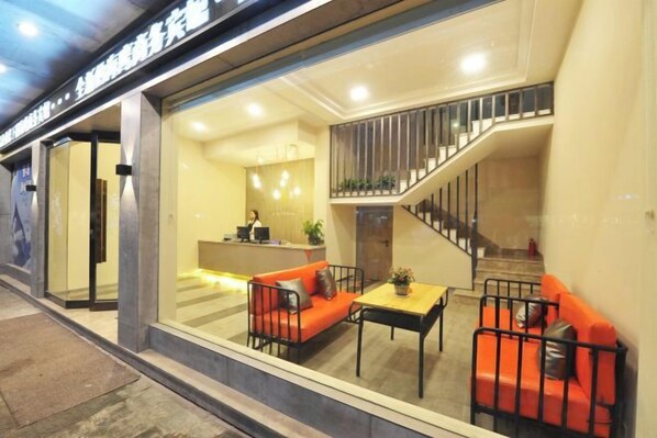 A hotel lobby with a reception desk, a staircase, and seating area with a sofa and a table.