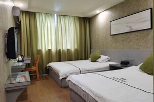 Habitación de hotel con dos camas, un escritorio, una silla, un televisor y una ventana con cortinas.