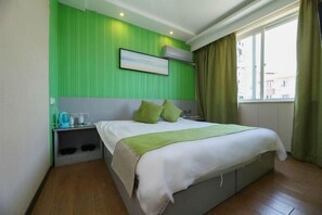 Quarto de hotel com cama, mesa de cabeceira, janela com cortinas e parede verde.