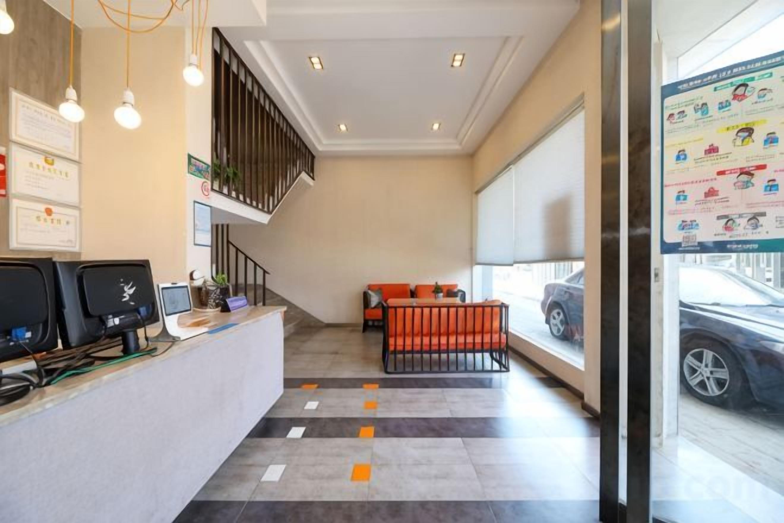 A reception area with a desk, chairs, a staircase, and a view of a parked car through a window.