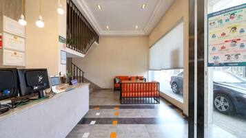 A reception area with a desk, chairs, a staircase, and a view of a parked car through a window.