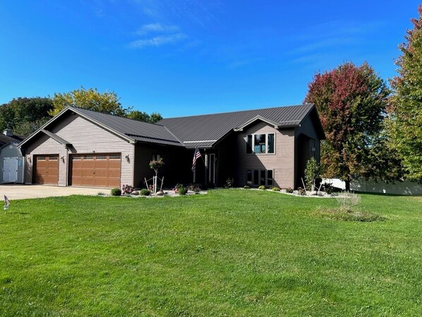 A two-story house with a garage, a covered driveway, and a well-maintained lawn.
