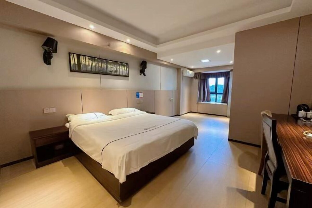 A bedroom with a bed, bedside table, and a window.