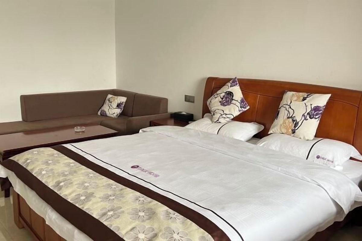 A hotel room with a bed, a sofa, and a small table.
