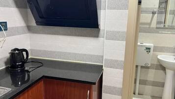 A kitchen with a black countertop, wooden cabinets, a coffee maker, a microwave, and a water dispenser.