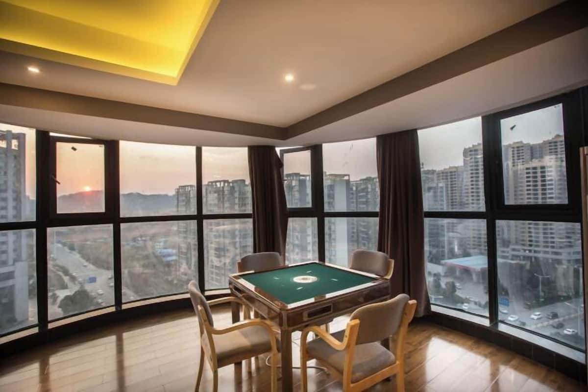 A room with a pool table, large windows, and a view of the cityscape.