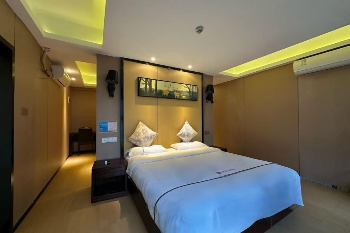 Une chambre d’hôtel avec un lit, des tables de chevet et une œuvre d’art accrochée au mur.