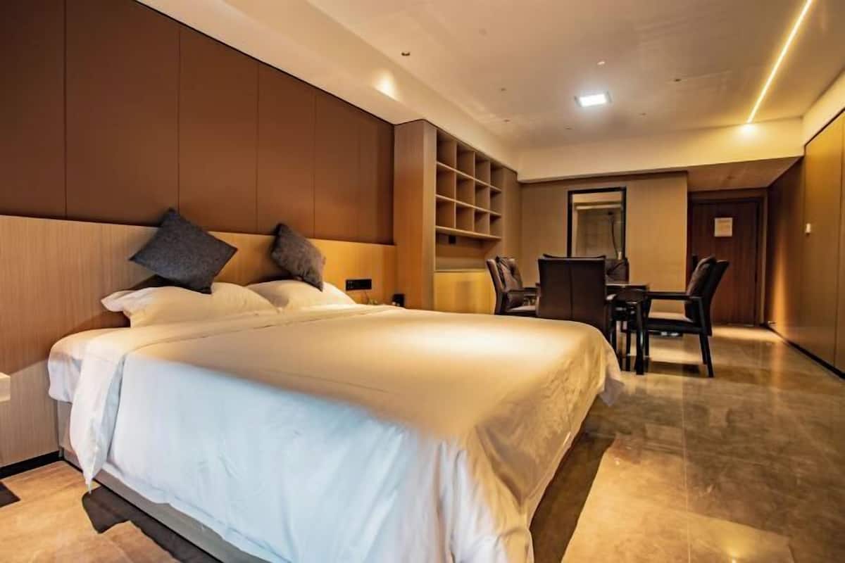 A hotel room with a large bed, a desk, and a chair.