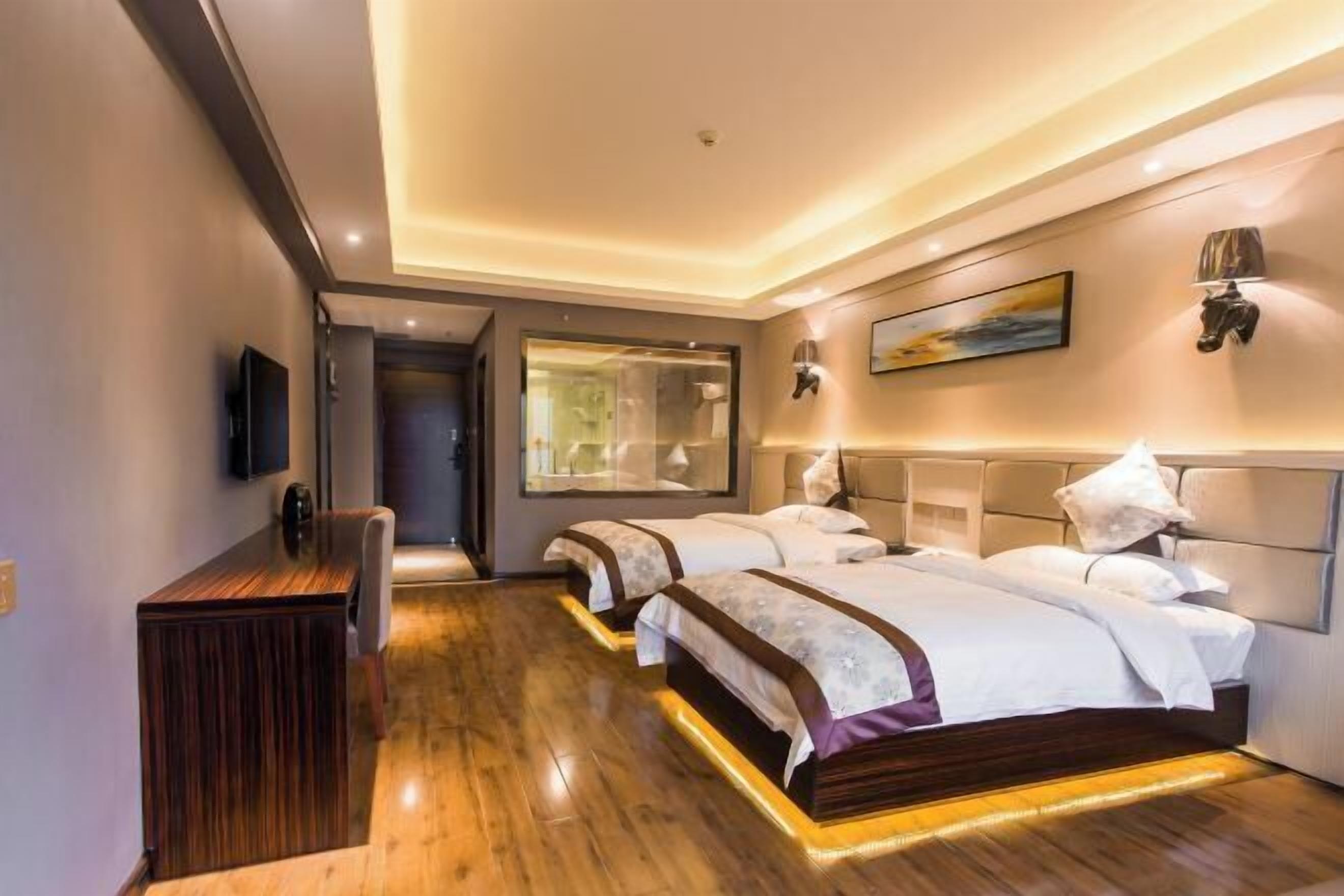A hotel room with two beds, a desk, a TV, and a large window.