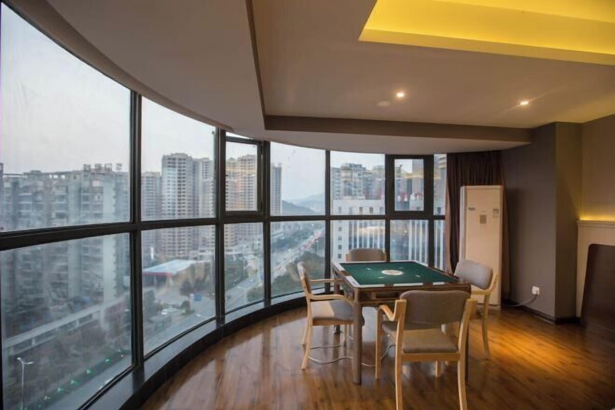 A room with a pool table, large windows, and a view of a cityscape.