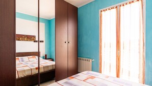 Ein Schlafzimmer mit Bett, Heizkörper und einem Fenster mit Vorhängen.