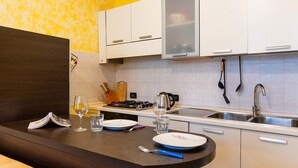 Eine moderne Küche mit weißen Schränken, einem Gasherd, einer Spüle und einem Essbereich mit dunkler Arbeitsplatte.