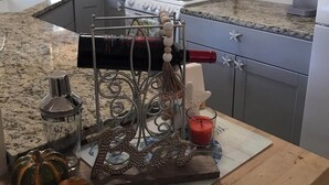 A kitchen with granite countertops, a stove, and cabinets. There is a decorative metal rack with a candle and a pumpkin on the counter.