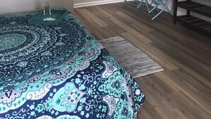 A bedroom with a bed, a desk, a chair, a TV, and a painting on the wall.