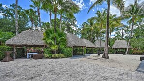 A tropical resort with thatched-roof huts, palm trees, and a paved walkway. - Beautifully RENOVATED 3 Bed/2.5 Bath Condo with ALL King beds in Ole at Lely!  (Naples)