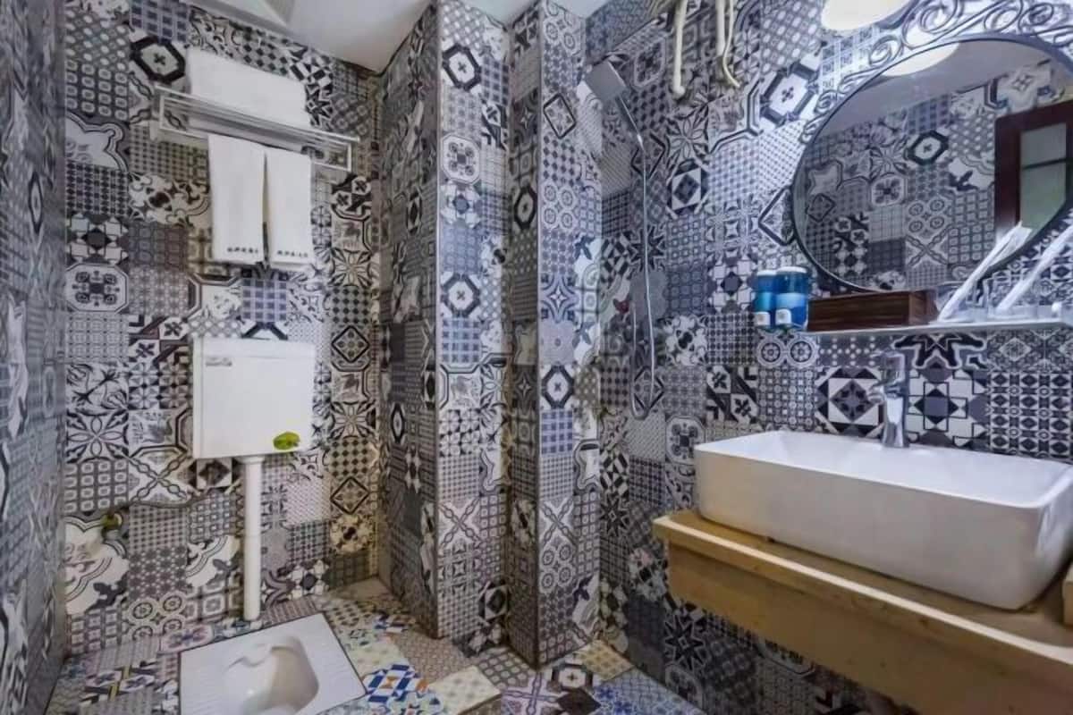 A bathroom with patterned tiles, a white sink, a mirror, and a toilet.