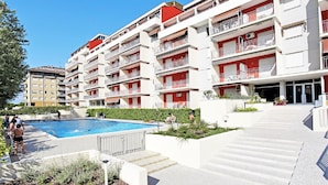Un hotel de varios pisos con balcones, piscina y un jardín ajardinado.