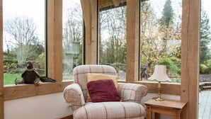 Un fauteuil à carreaux avec un coussin, une petite table en bois et une lampe.