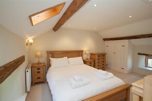 A bedroom with a wooden bed, bedside tables with lamps, a wardrobe, and a window. - Old Droomer (Windermere)