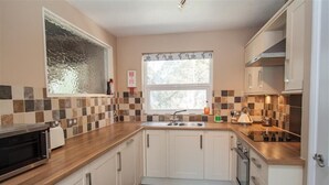 A modern kitchen with white cabinets, a microwave, a stove, and a sink. - Mellbreak (Ambleside)