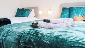 A hotel room with a bed, two bedside lamps, and a green bedspread.