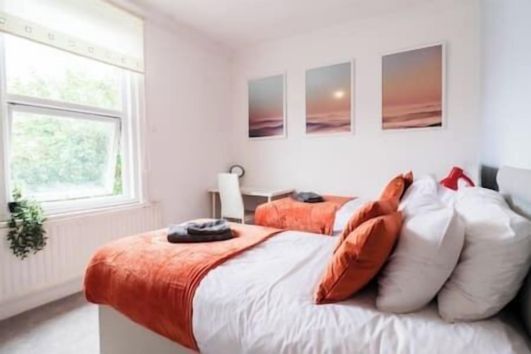 A bedroom with a bed, pillows, a bedside table, and a window.