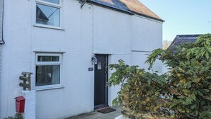 A white two-story house with a black door, a small window, and a red mailbox. - Oscar's Pad (Llanfairpwllgwyngyll)