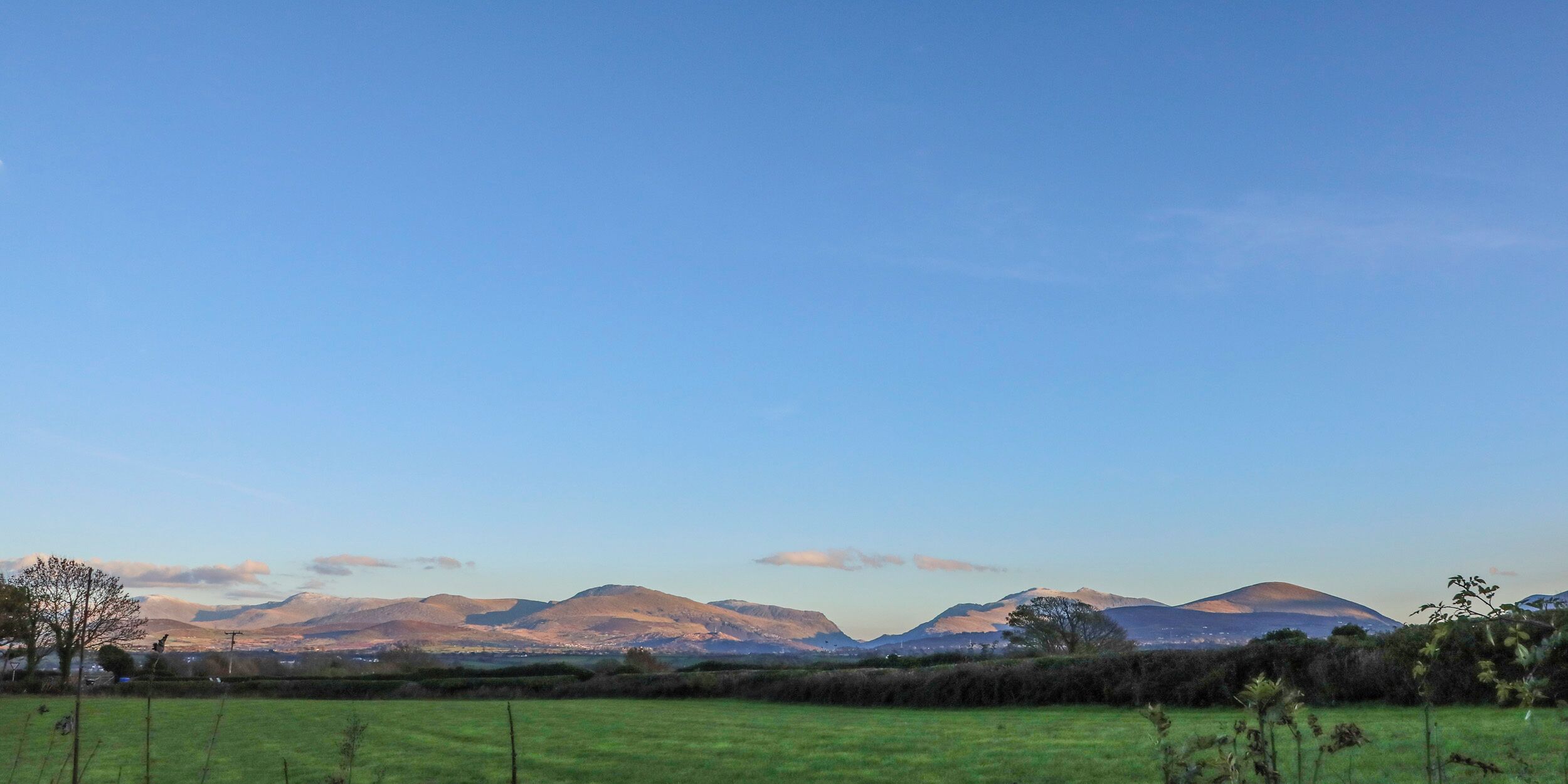 A wide, open field with distant mountains under a clear sky.