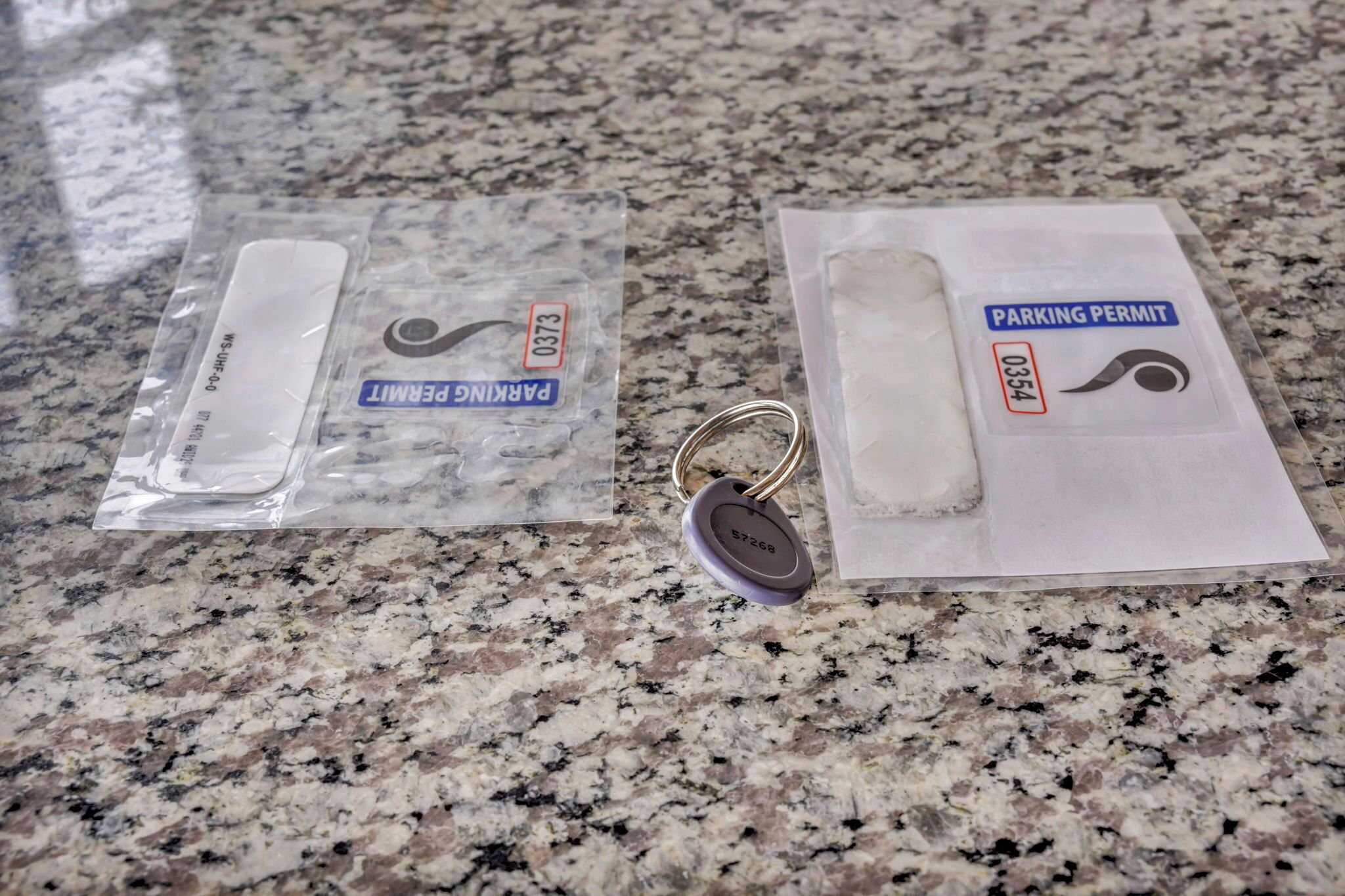 Two plastic packages on a granite countertop, one labeled "Parking Permit" and the other "Parking Permit."