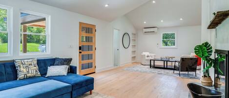 Un salón amplio con un sofá azul, suelo de madera y una chimenea.