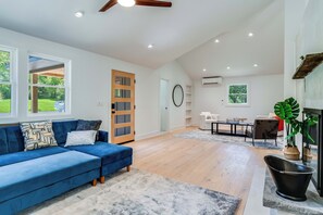 Un salon spacieux avec un canapé bleu, un plancher en bois et une cheminée.