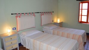 Une chambre avec deux lits, une table de chevet avec une lampe et une fenêtre donnant sur un beau paysage.